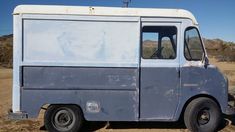 an old blue truck is parked in the dirt