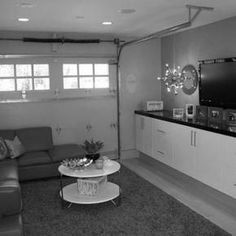 a black and white photo of a living room with two couches, a coffee table and a flat screen tv