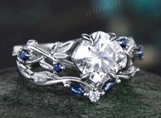 a diamond and blue sapphire ring on top of a rock