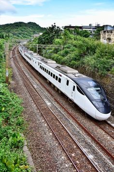 a train traveling down tracks next to a lush green hillside