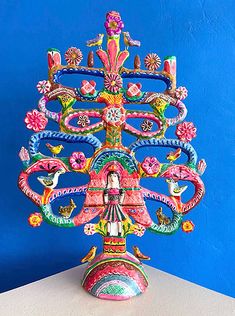 a colorfully decorated vase sitting on top of a white table next to a blue wall