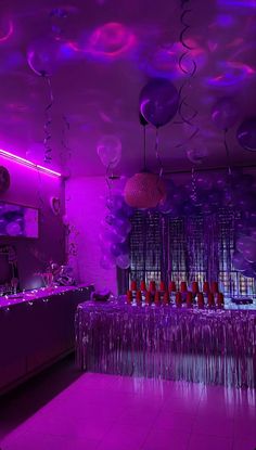 a room filled with lots of purple balloons and streamers hanging from the ceiling above it