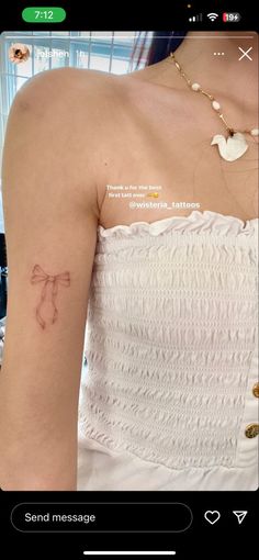 a woman's arm with a small tattoo on the left side of her shoulder