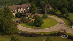 an aerial view of a large house with lots of trees and people walking around it