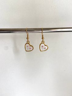 These stunning earrings are the perfect accessory to complete any outfit, and they are sure to make you look and feel your very best! Each earring features two delicate, real pressed flowers preserved in clear resin inside of a small, gold heart charm. You can choose from 24k gold plated wire (comes with rubber earring back), 24k gold plated leverback (huggies), or clip on earrings (no piercing needed). If you would like a combination of flower colors, please specify in the personalization box w Dainty Dangly Earrings, White Dainty Heart Earrings For Pierced Ears, Dainty White Heart Earrings For Pierced Ears, White Heart Drop Earrings For Mother's Day, White Heart Earrings With Ear Wire As A Gift, Minimalist White Earrings For Valentine's Day, White Hypoallergenic Heart Drop Earrings, Delicate Drop Earrings For Valentine's Day, White Flower Earrings For Valentine's Day