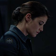 a woman in uniform looking down at her cell phone while staring into the distance with an intense look on her face