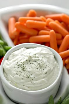 carrots and celery sticks with dip in a white bowl on a plate