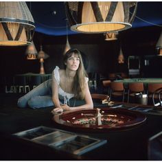 a woman laying on the ground in front of a table with food and lights hanging from it