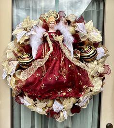 a red and gold wreath with angel figurines hanging from it's front door