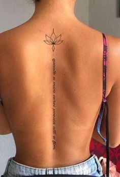 the back of a woman's neck with a lotus tattoo on her lower back