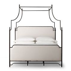 an iron bed frame with white linens and pillows on the bottom, against a white background