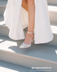 a woman in high heels is sitting on the steps wearing a white dress and coat