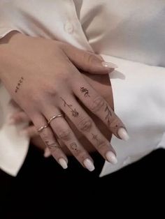 a woman's hands with tattoos on her left hand and two fingers, both holding each other