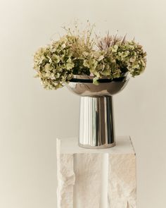 a silver vase with some flowers in it