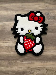 a hello kitty rug with a strawberry in its hand on a wooden floor next to wood planks