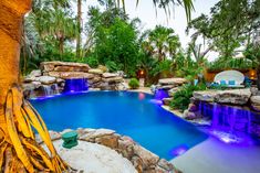 an outdoor swimming pool surrounded by palm trees and water features waterfalls, rocks, and lights