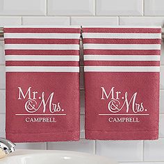 two personalized red towels hanging on a towel rack next to a white bathroom sink