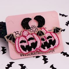 two pink and black earrings are sitting on top of a piece of paper with bats