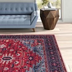 a blue couch sitting next to a red rug on top of a hard wood floor