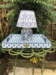 a blue and white tray with a lamp on it sitting in front of some plants