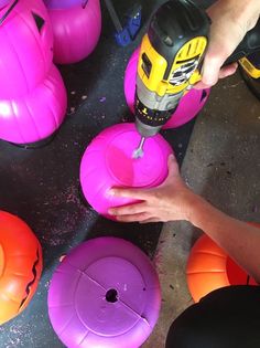 a person is sanding inflatable balls on the ground with a driller