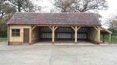 a large wooden building sitting on top of a parking lot next to trees and grass