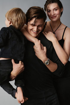 a man and woman holding a small child in their arms while smiling at the camera