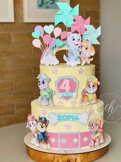 a three tiered cake decorated with cartoon characters and balloons on top of a table