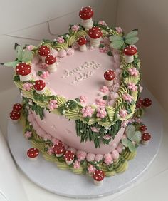 a pink cake decorated with flowers and mushrooms