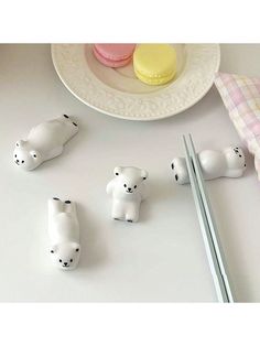 four small white polar bears next to some chopsticks and a plate with macaroni and cheese on it