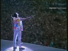 a man standing on top of a stage with his arms out in front of an audience