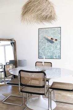 a dining room table with chairs and a painting on the wall