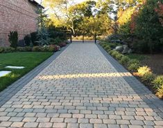 a brick walkway in the middle of a yard with grass and flowers on either side