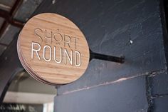 a wooden sign that says short round hanging from the side of a building