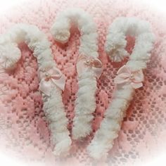 three white fluffy toothbrushes with bows on them sitting next to each other in front of a pink background