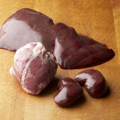 three pieces of meat sitting on top of a wooden cutting board next to an uncooked piece of meat