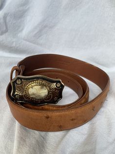 "You are looking at a genuine gold tone buckle with a lovely stone. Buckle measures 2\"6 wide X 1\"5 high. The ostrich belt is size 38 and measures 43\"7 long with 35\"8 on first perforation from buckle and 39\"8 on last perforation. The overall condition of this genuine ostrich belt is good and there are a few light scuffs with no tears and is made in USA. I WANT TO STRESS THAT THIS ITEM IS VINTAGE WHICH MEANS IT'S NOT NEW. IF YOU'RE LOOKING FOR A NEW BAG PLEASE DON'T BID AND WHAT YOU ARE BIDDI Bell Gardens, Vintage Western, Belt Size, New Bag, Dooney Bourke, Black And Tan, Tan Leather, Leather Belt, Leather Shoulder Bag