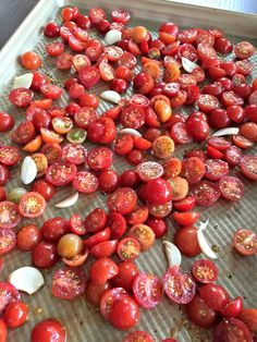 tomatoes and garlic on a baking sheet ready to be cooked in the oven for roasting