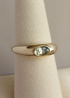 Risa is a solid, signet-style ring with a soft, smooth touch. The original inspiration came from an early 14th century British stirrup ring. I plumped it up to add a luxurious weightiness and added a pool of color at is peak. STONES• 0.60ct oval brilliant-cut light green Montana Sapphire• Origin: Responsibly sourced direct from the miner from Montana, USA• Stone is flush set MATERIAL• Tapers from 6mm down to 2.5mm at the base• Made from 100% SCS certified recycled solid gold PROCESS• Please allo Antique Signet Ring, Signet Engagement Rings, Concrete Wedding, Flush Ring, Green Montana, Montana Usa, Fall Rings, Birthday Ring, Dream Engagement Rings