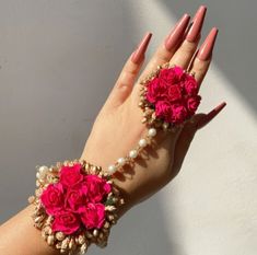 a woman's hand with red flowers and pearls on it