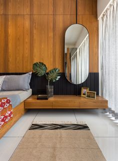 a bedroom with a bed, mirror and plant on the side table in front of it