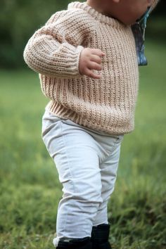 a baby wearing a sweater and white pants