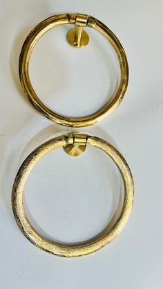 two gold colored metal rings on a white surface