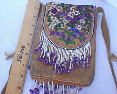 an old purse with beaded flowers on it and a measuring ruler next to it