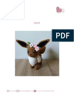 a small stuffed animal with flowers on it's head sitting on a wooden table