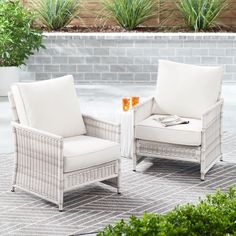 two white wicker chairs sitting next to each other on top of a tile floor