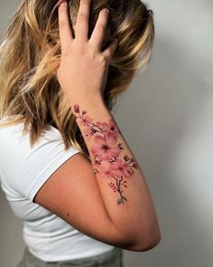 a woman with a tattoo on her arm holding her hand up to her face and looking at the camera