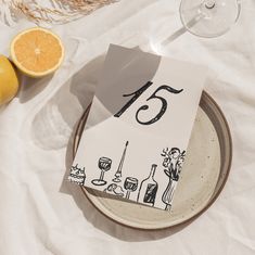 a plate with a napkin on it sitting next to some oranges and wine glasses