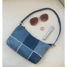 a denim purse with sunglasses, nail polish and an earring laying on top of it