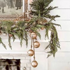 a mantel decorated with christmas ornaments and greenery in front of a fire place